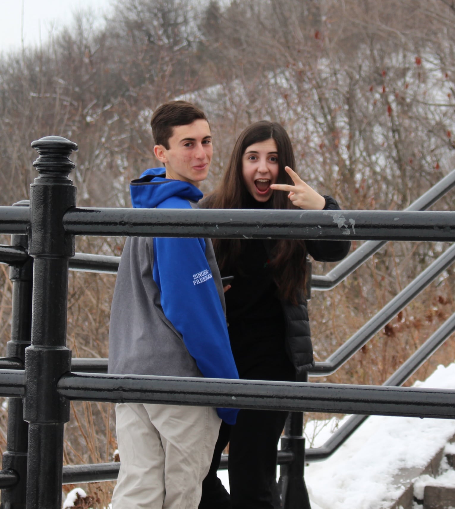 Ari and Montana on a snowy staircase, Montana making a peace sign