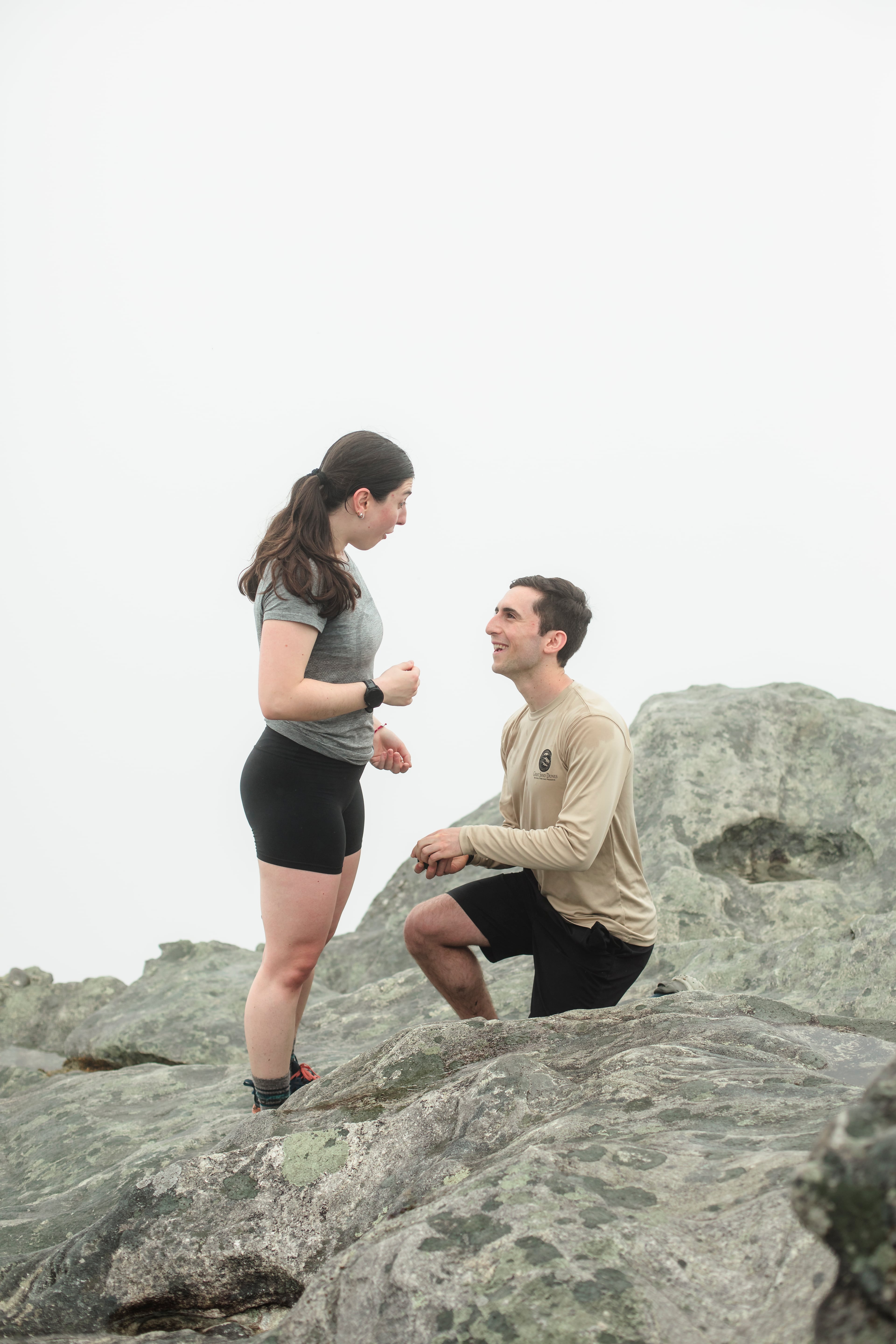Ari on one knee proposing to Montana on a misty mountaintop